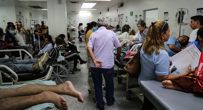 Pacientes ficam aglomerados em macas ou cadeiras de rodas ao longo do corredor, porque faltam leitos