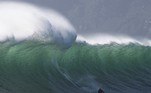 Um surfista pega uma onda no Sunset, um local de surf próximo a Hout Bay, que produz algumas das maiores ondas da África do Sul na Cidade do Cabo, em 22 de agosto