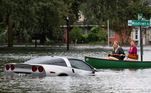 Em Orlando, mulheres usam bote para se locomover em enchente enquanto observam um Corvette flutuando na água