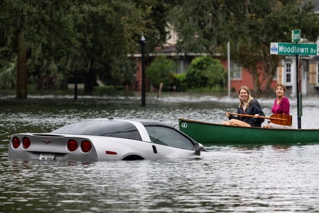 Em Orlando, mulheres usam bote para se locomover em enchente enquanto observam um Corvette flutuando na água