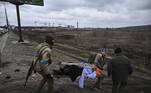 Idosa é retirada em uma maca por soldados ucranianos na cidade de Irpin