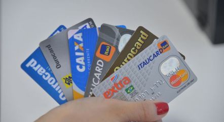 Mão feminina segura seis cartões de crédito