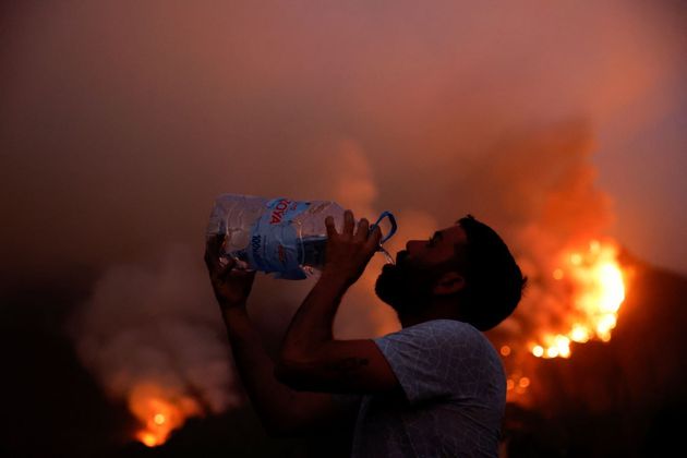 Residente da cidade de Aguamansa bebe água enquanto incêndios florestais saem de controle na ilha de Tenerife (Espanha)