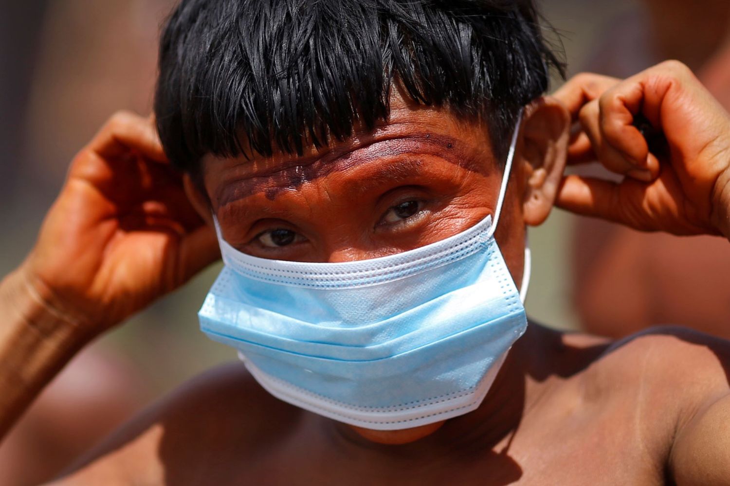 Indígena do povo ianomâmi segura máscara de proteção em Alto Alegre, Roraima 