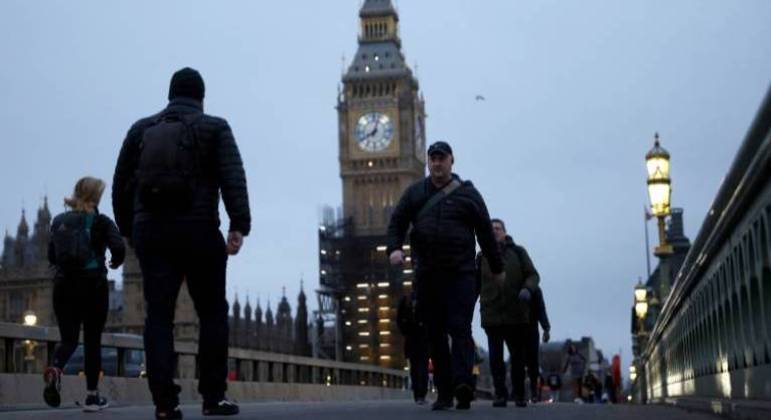 Pedestres caminham sobre a ponte de Westminster em meio à pandemia de Covid-19