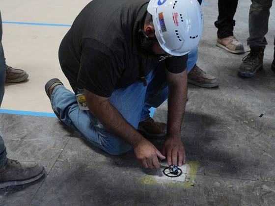 Durante uma sessão de treinamento, um instrutor define um refletor que alinha um laser com um robô que desenha linhas de layout com mais precisão e eficiência do que os trabalhadores que usam uma linha de giz