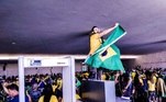 Manifestante é flagrado segurando a bandeira do Brasil, após invadir a sede dos três poderes em Brasília.