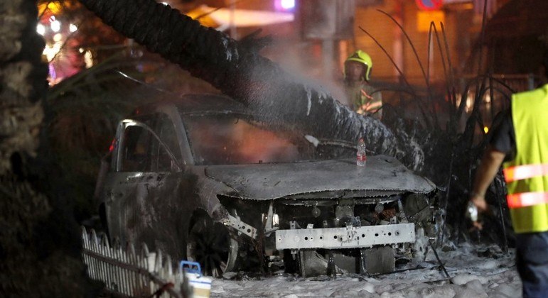 Bombeiros apagam incêndio em carro atingido por foguete em Holon, perto de Tel Aviv
