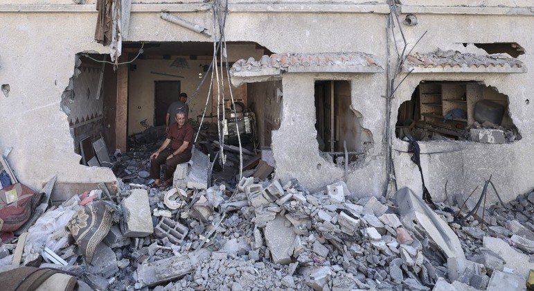 Homem palestino sentado dentro de sua casa, atingida em ataques na cidade de Gaza