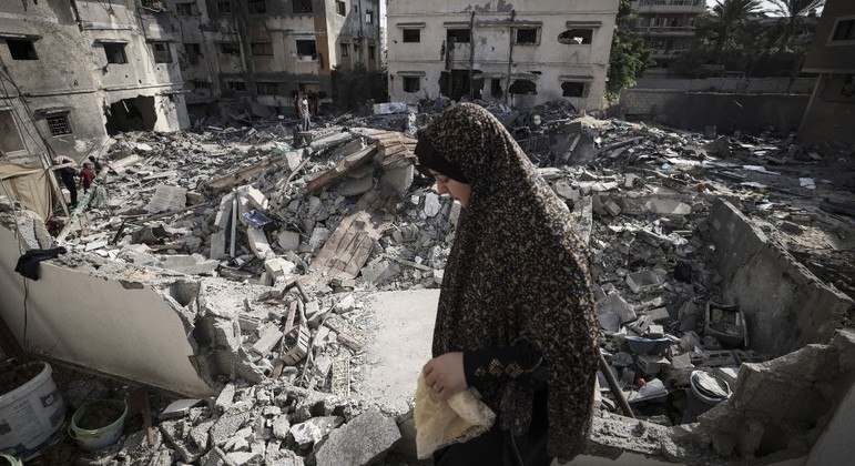 Mulher palestina em meio a escombros após ataques israelenses na cidade de Gaza