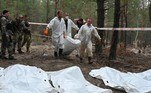 À direita da trilha, 100 metros dentro da floresta, segundo jornalistas da AFP, dois homens (de túnica branca) cavaram delicadamente a areia no fundo de uma sepultura, que tinha uma cruz e a inscrição: 'Exército ucraniano 17 pessoas. Izium, do necrotério'