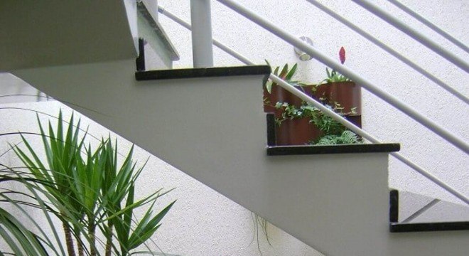 Jardim de inverno sob a escada com banco de madeira de dois lugares e chão de pedras