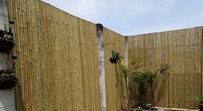 Jardim externo delimitado com cerca de bambu