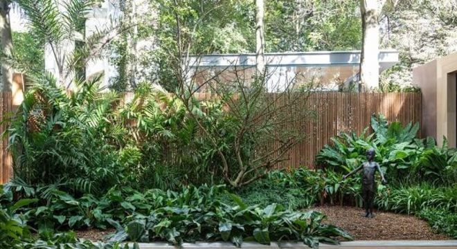 Jardim residencial com cerca de bambu ao fundo