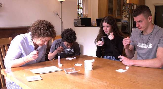 Jayne e seus três filhos adolescentes, Sam, Meg e Billy, cuspindo em uma colher para realizar teste de coronavírus