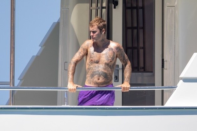 De bermuda roxa, Justin ficou sem camisa durante o passeio de barco e exibiu suas diversas tatuagens pelo corpo