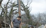 Dois voluntários cortam uma árvore que caiu por causa da força dos ventos
