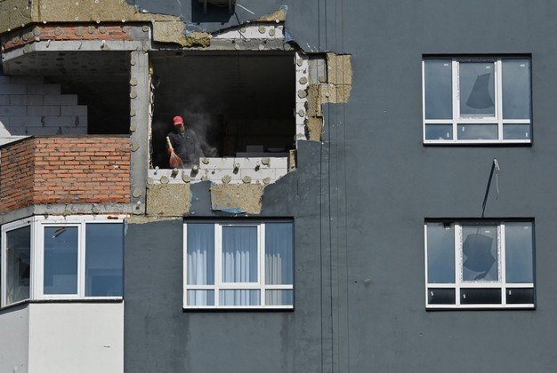 No último andar parcialmente destruído de um prédio residencial em Irpin, um subúrbio de Kiev devastado pela guerra, Mykhaylo Kyrylenko observa orgulhosamente o novo telhado tomar forma