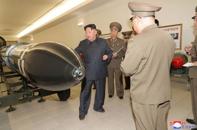 O líder norte-coreano Kim Jong-un defendeu o aumento da produção de armamento e também a fabricação de armas mais potentes, anunciou a imprensa estatal. O apelo de Kim coincide com a chegada de um porta-aviões americano à Coreia do Sul nesta terça-feira (28)Na foto, Kim, junto com militares, posa ao lado de uma suposta arma nuclear do arsenal de seu país