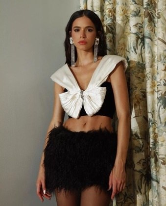 Bruna Marquezine esbanjou estilo ao combinar um top cropped em formato de laço, deixando a barriga à mostra, com uma minissaia de plumas