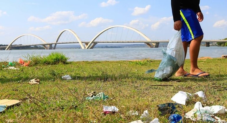 Homem catando lixo nas margens do Lago Paranoá
