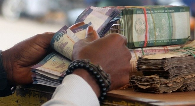Mulher conta maços de dólares liberianos em Monróvia, a moeda perdeu valor