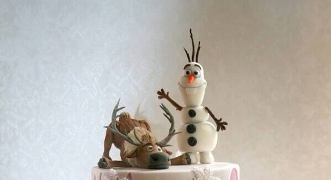 lindo bolo da frozen decorado com personagens no topo e detalhes metalizados 