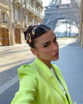 A influenciadora Livia Marques ousou com um coque cheio de gel e presilhas coloridas, durante um passeio em Paris, na França