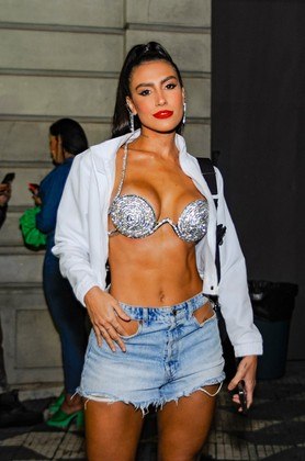 Any Borges está entre as famosas que fugiram da cor preta. O destaque do look foi o biquíni metalizado e diferentão. Jaqueta branca e saia jeans com recortes completaram o visual