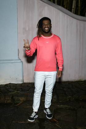 Rene Silva também esbanjou estilo com um visual casual: camisa rosa neon de manga longa, calça branca e tênis preto de sola branca