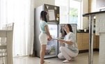 Mãe e filha na cozinha, em frente à geladeira com a porta aberta. Freepik