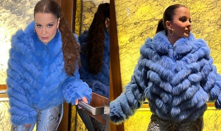 Maiara, que faz dupla com Maraisa, escolheu uma blusa azul de plumas, calça estampada com desenhos de pele de cobra e botas brancas para posar superestilosa dentro de um elevador espelhado