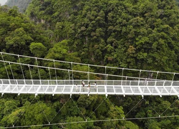 A ponte está suspensa 150 metros acima de uma selva no Moc Chau Island Mountain Park and Resort. A estrutura está em torno de penhascos vertiginosos e atravessa um vale entre dois picos