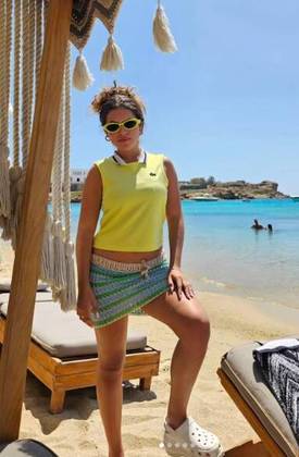 Já para aproveitar uma praia na ilha grega, ela optou por um look meio esportivo, meio artesanal, todo trabalhado nas cores do Brasil. O visual uniu camisa regata, minissaia de crochê, chinelo Crocs e óculos de sol