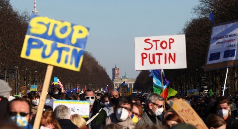 Pessoas carregam bandeiras e cartazes durante manifestação anti-guerra em Berlim