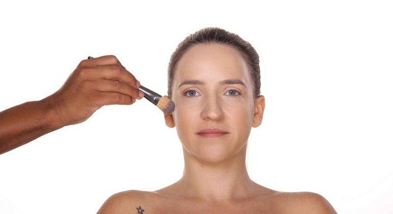 1. Após limpar e preparar a pele, aplique uma base cremosa em todo o rosto de maneira uniforme