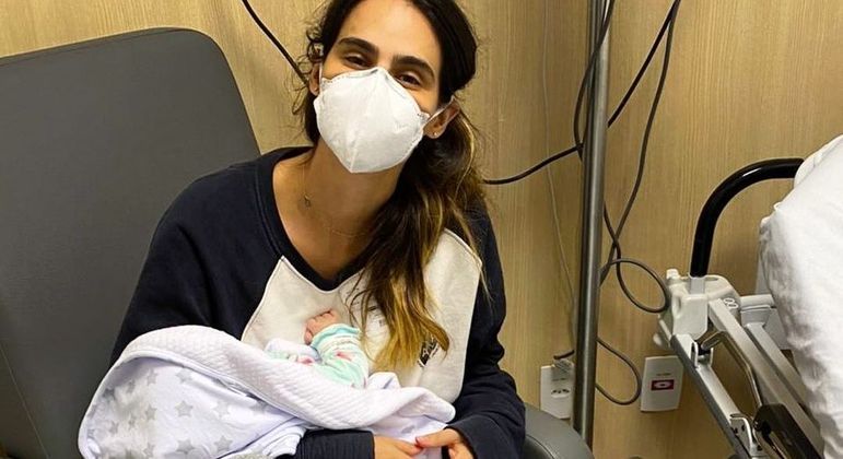 Marcella Fogaça segurando a filha no hospital

