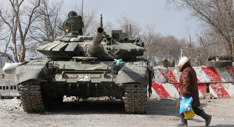 Um morador local passa por um tanque de tropas pró-Rússia em Mariupol