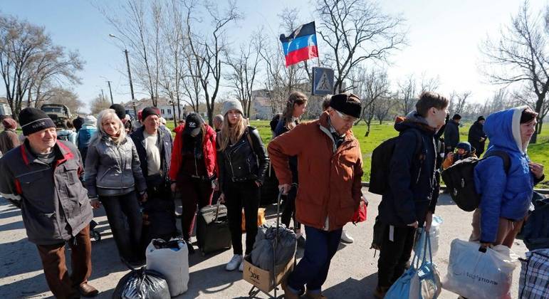 Ucranianos esperam antes de embarcar em um ônibus para deixar a cidade de Mariupol 