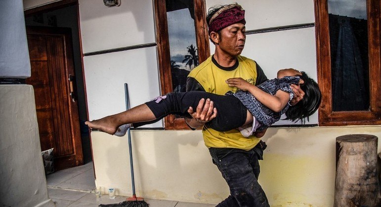 Homem carrega sua filha ferida após terremoto de magnitude 5,6 na Indonésia