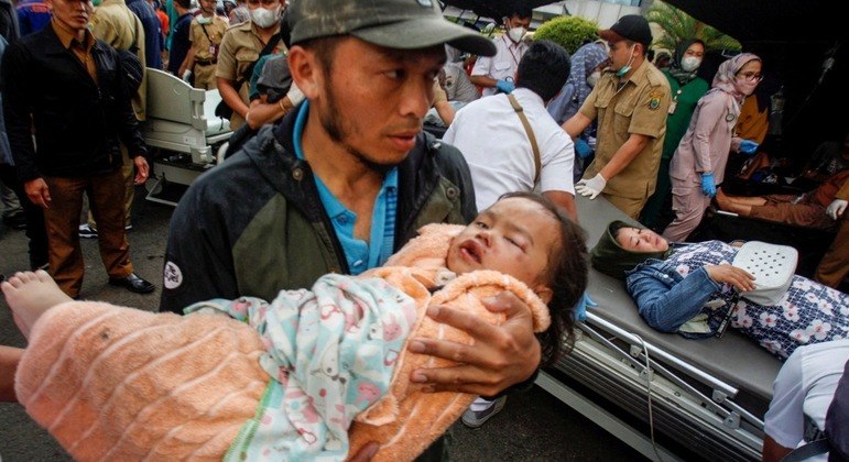 Homem carrega uma criança ferida após terremoto na Indonésia