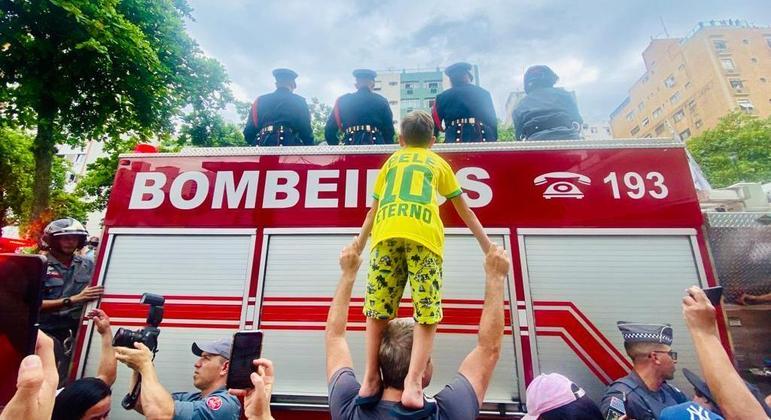 Gabriel Corregio, 7 anos, é erguido pelo pai, Ricardo, na passagem do cortejo em Santos