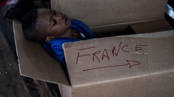 Un niño en una caja con la palabra «Francia» a bordo de un barco que transportaba a 230 inmigrantes rechazados por Italia
