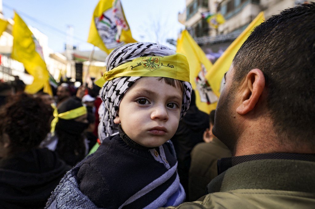 Homem palestino carrega uma criança enquanto participa de uma manifestação na Cisjordânia