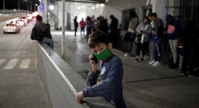 Menino fala ao telefone na fronteira entre México e Estados Unidos