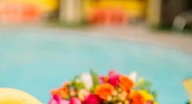 mesa de comidas para festa na piscina decorada com flores