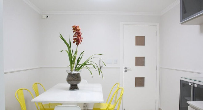 Mesa retangular branca e cadeiras amarelas para o ambiente de cozinha