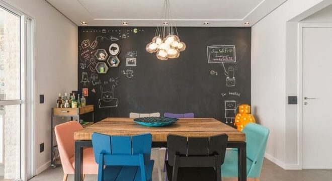 Mesa retangular de madeira acomoda seis pessoas no ambiente