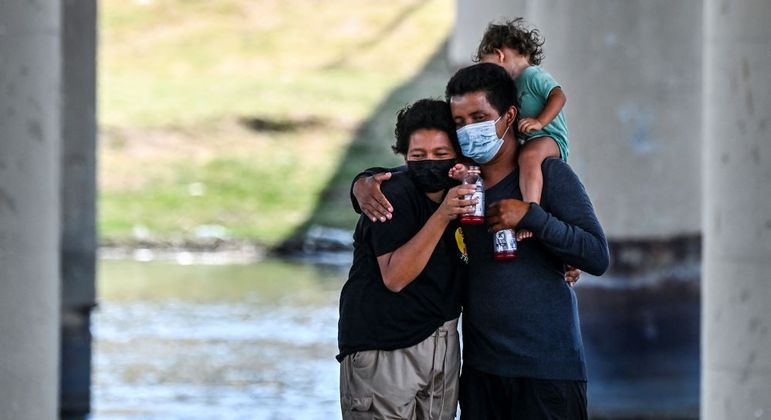 Casal de migrantes com uma criança perto da fronteira do México com o Texas, nos EUA
