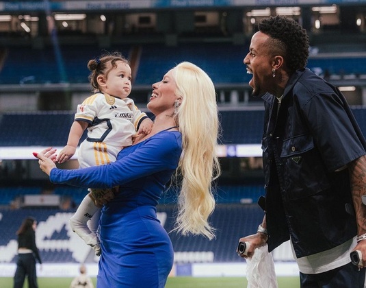 O zagueiro Éder Militão segue em recuperação da cirurgia que fez para reconstituir o ligamento do joelho esquerdo, rompido no dia 12 de agosto em partida contra o Athletic Bilbao pelo campeonato Espanhol. Mas neste sábado (02), ele fez questão de ir ao estádio Santiago Bernabeu para acompanhar a vitória do Real Madrid contra o Getafe por 2 a 1. O detalhe que mais chamou atenção foi com quem ele esteve ao estádio. Acompanhado da filha Cacília e da ex-mulher Karoline Lima os três registraram o momento família em sessão de fotos no gramado da arena